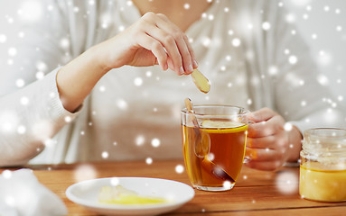 Image showing close up of woman adding honey to tea with lemon