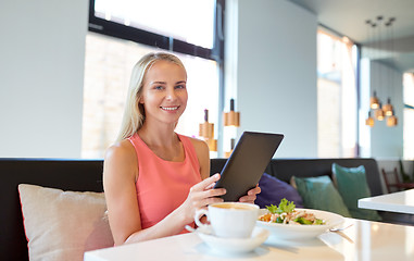 Image showing happy young woman with tablet pc at restaurant