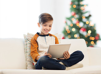 Image showing smiling boy with tablet pc at home at christmas