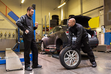 Image showing auto mechanics changing car tires at workshop