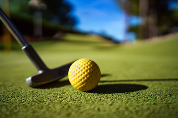 Image showing Mini Golf yellow ball with a bat at sunset