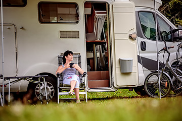 Image showing Woman is standing with a mug of coffee near the camper RV.