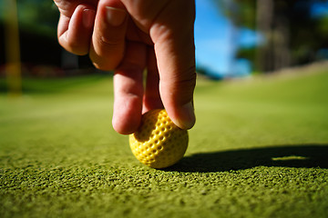 Image showing Mini Golf yellow ball on green grass at sunset