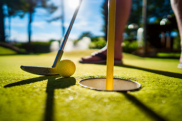 Image showing Mini Golf yellow ball with a bat near the hole at sunset