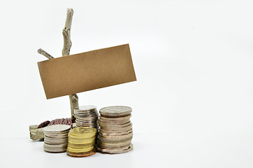 Image showing Paper sign board with stack of coins