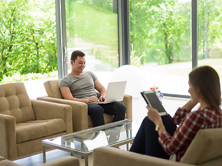 Image showing couple relaxing at  home with tablet and laptop computers