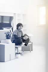 Image showing boy sitting on the table with cardboard boxes around him