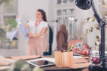 Image showing Fashion designers working in studio sitting on the desk