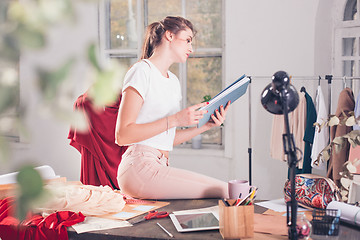 Image showing Fashion designers working in studio sitting on the desk