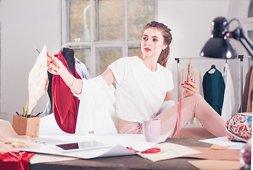 Image showing Fashion designers working in studio sitting on the desk