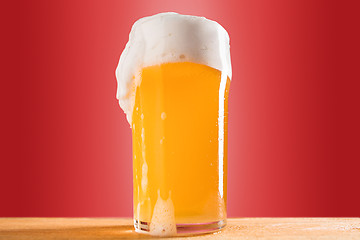 Image showing glass of cold frothy lager beer on an old wooden table