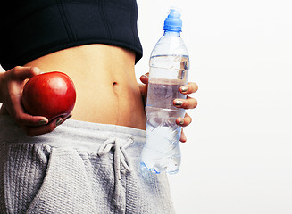 Image showing close up woman stomach with hands holding water and reg apple