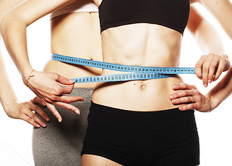 Image showing two sport girls measuring themselves isolated on white