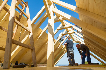 Image showing Builders at work with wooden roof construction.