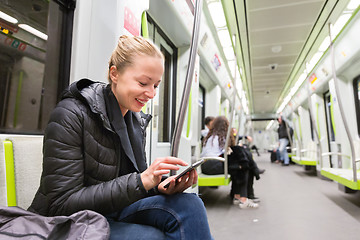 Image showing Young girl reading from mobile phone screen in metro.