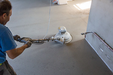 Image showing Laborer polishing sand and cement screed floor.