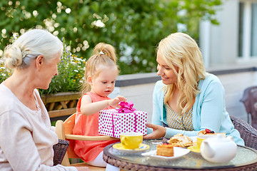 Image showing happy mother giving present to daughter at cafe