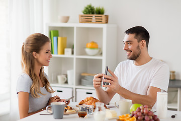 Image showing couple with smartphones having breakfast at home