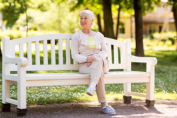 Image showing happy senior woman sitting on bench at summer park