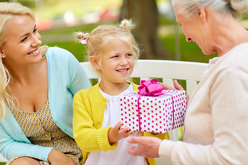 Image showing happy family giving present to grandmother at park