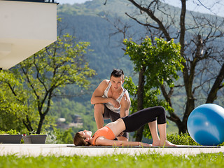 Image showing woman with personal trainer doing morning yoga exercises