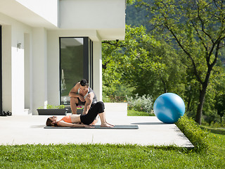 Image showing woman with personal trainer doing morning yoga exercises