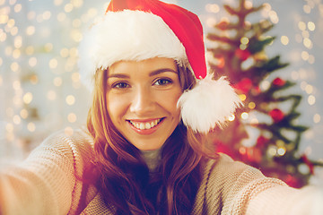 Image showing happy woman taking selfie over christmas tree