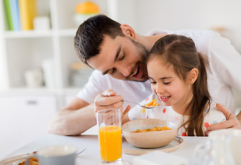 Image showing happy family eating flakes for breakfast at home