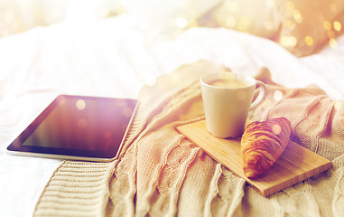 Image showing tablet pc, coffee and croissant on bed at home