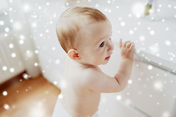 Image showing happy little baby boy or girl holding to table