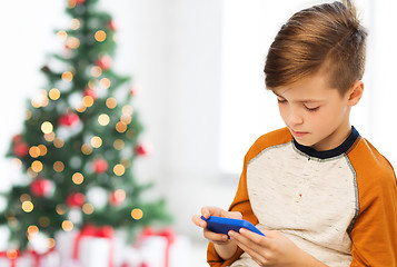 Image showing close up of boy with smartphone at christmas