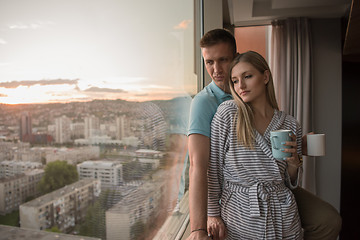 Image showing young couple enjoying evening coffee by the window