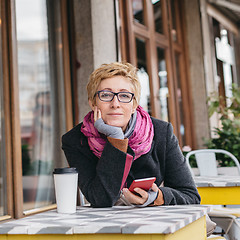 Image showing Dreamy woman with phone in cafe