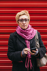 Image showing Woman with phone at red fence