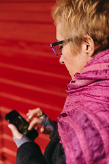 Image showing Woman texting at red wall