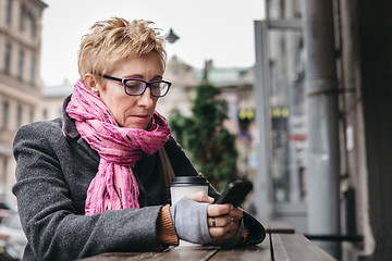 Image showing Woman browsing smartphone in outside cafe