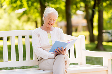 Image showing happy senior woman reading book at summer park