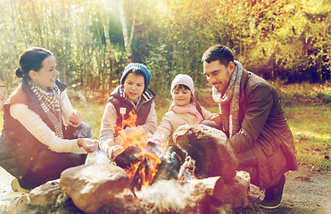 Image showing happy family roasting marshmallow over campfire