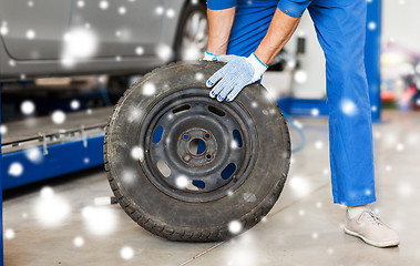 Image showing auto mechanic changing car tire at workshop