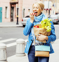 Image showing young pretty blond woman with food in bag walking on street