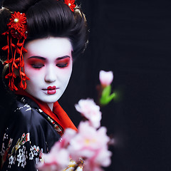 Image showing young pretty geisha in kimono with sakura and decoration