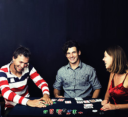 Image showing young people playing poker on black background