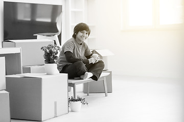 Image showing boy sitting on the table with cardboard boxes around him