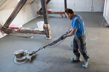 Image showing Laborer polishing sand and cement screed floor.