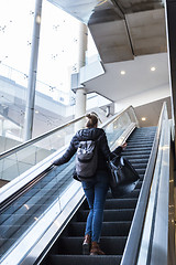 Image showing Businesswoman with large black bag and mobile phone ascending on escalator.