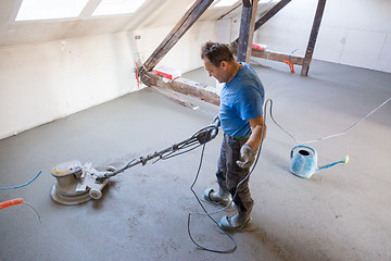 Image showing Laborer polishing sand and cement screed floor.