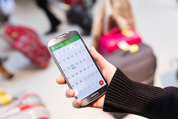 Image showing Woman checking calendar information on mobile phone sitting in airport terminal.