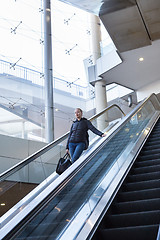 Image showing Businesswoman with large black bag and mobile phone descending on escalator.