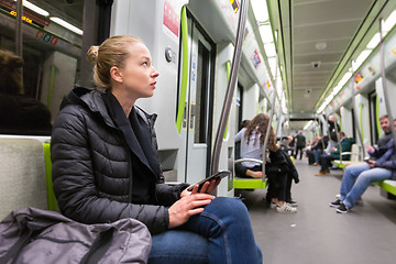 Image showing Young girl with mobile phone traveling on metro.