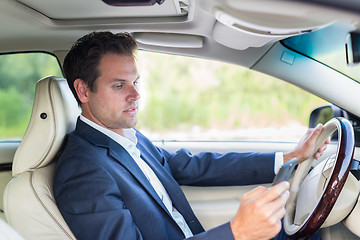 Image showing Businessman using cell phone and texting while driving not paying attention to the road.